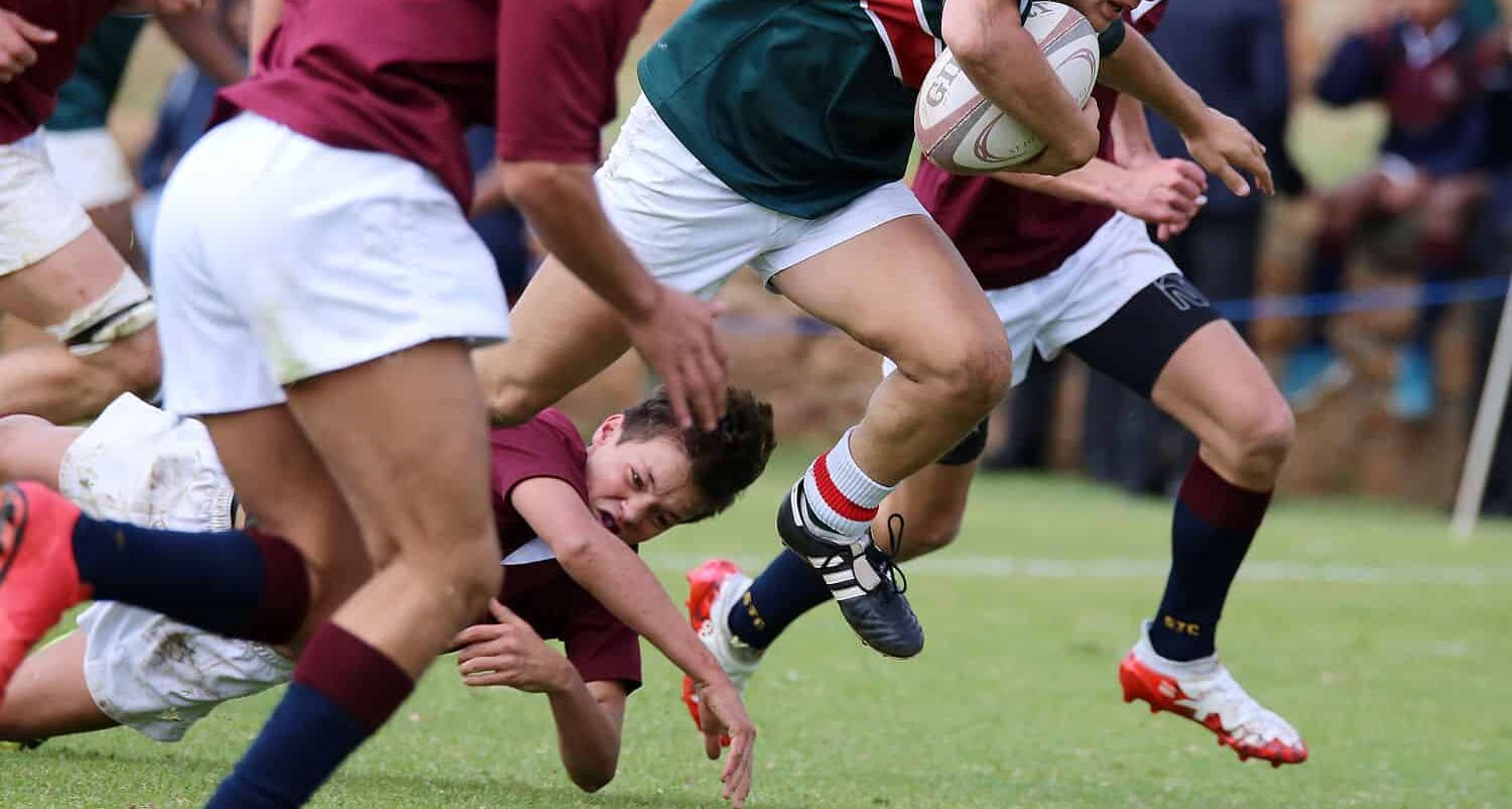 A close-up of a tennis net on a grass court in Salt Lake City, with a white strap securing the center to the ground and crisp white lines marking the sports field—perfect for natural or artificial turf installation.