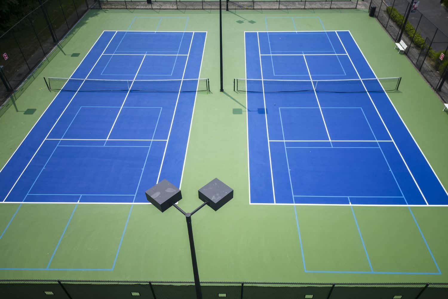 A close-up of a tennis net on a grass court in Salt Lake City, with a white strap securing the center to the ground and crisp white lines marking the sports field—perfect for natural or artificial turf installation.
