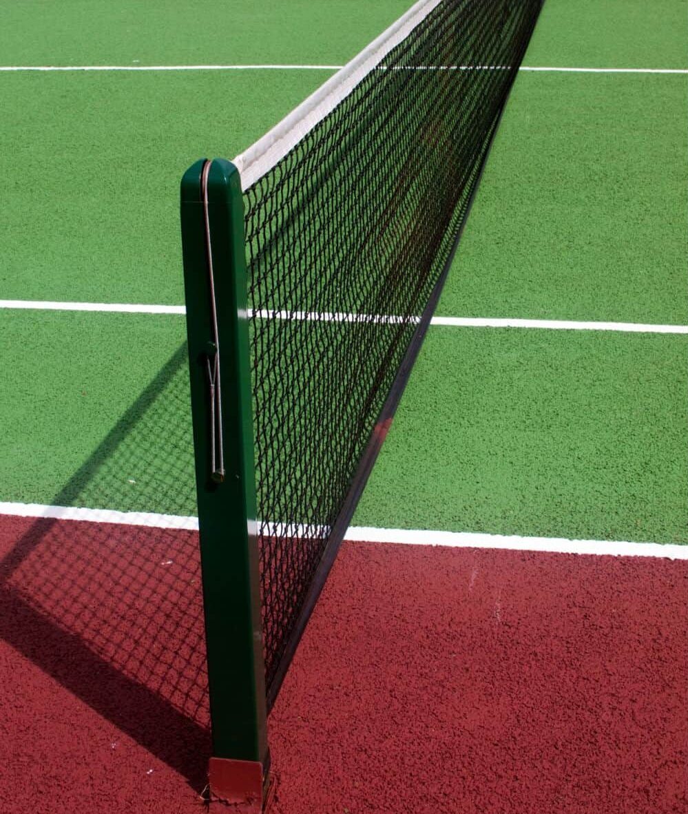 A close-up of a tennis net on a grass court in Salt Lake City, with a white strap securing the center to the ground and crisp white lines marking the sports field—perfect for natural or artificial turf installation.