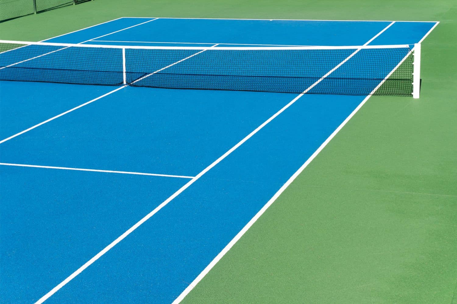 A close-up of a tennis net on a grass court in Salt Lake City, with a white strap securing the center to the ground and crisp white lines marking the sports field—perfect for natural or artificial turf installation.