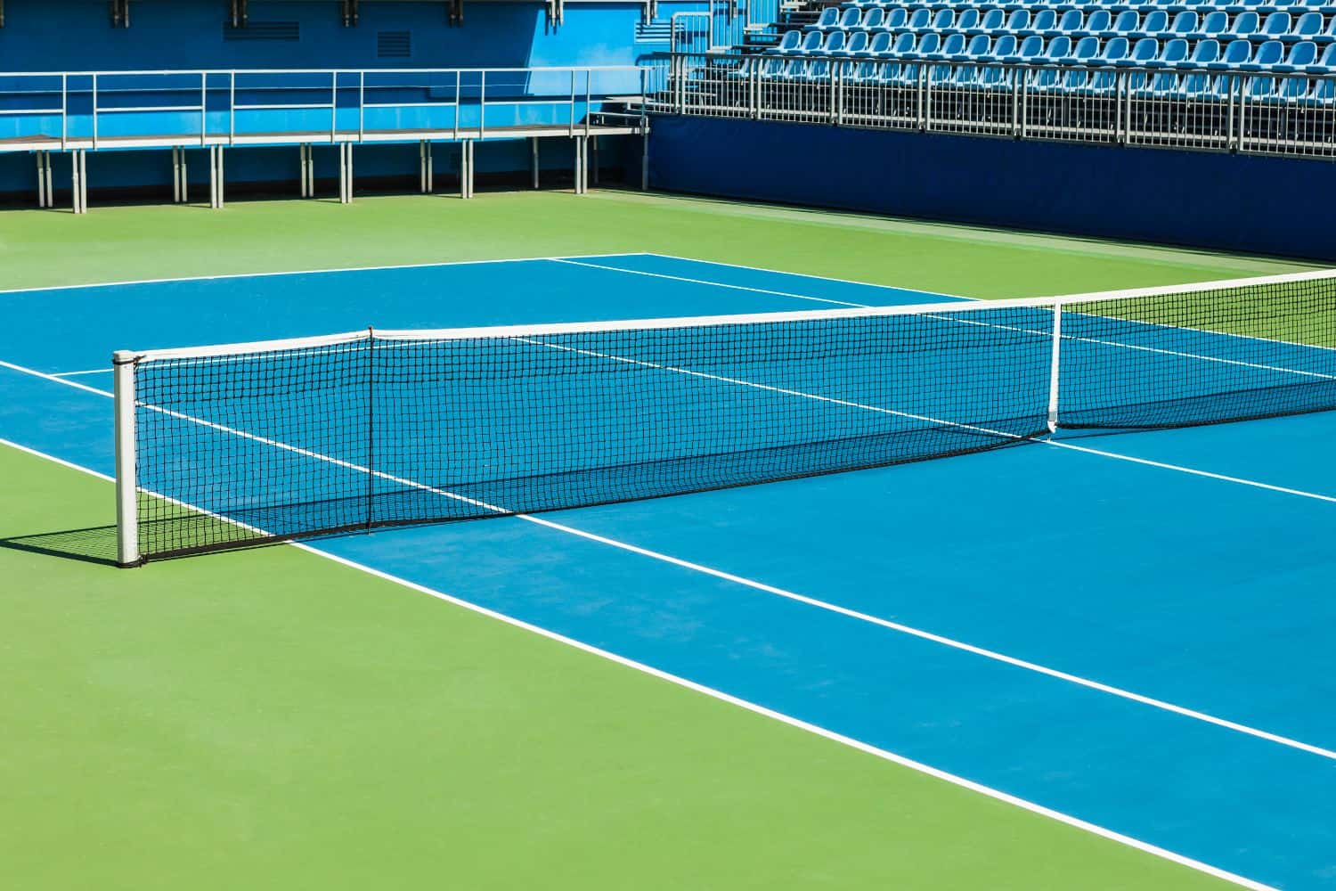 A close-up of a tennis net on a grass court in Salt Lake City, with a white strap securing the center to the ground and crisp white lines marking the sports field—perfect for natural or artificial turf installation.